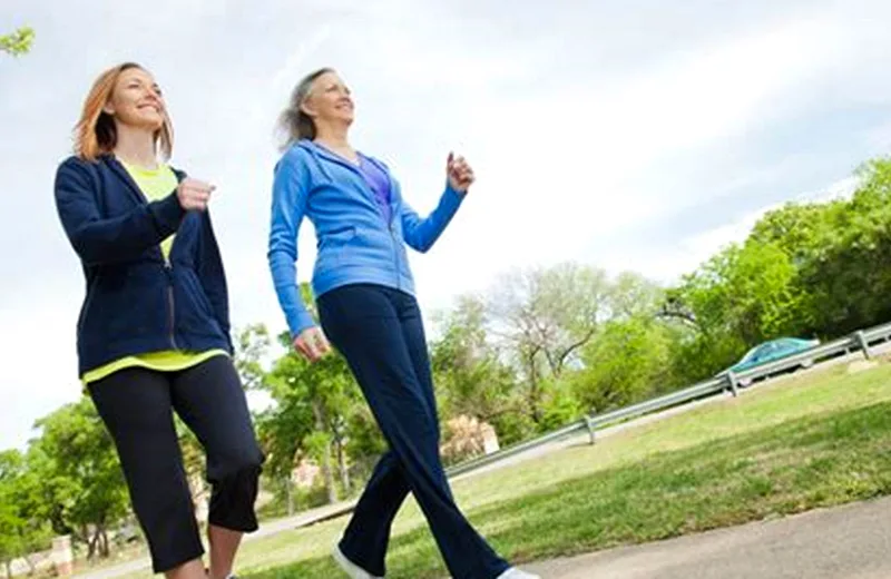 A confident postmenopausal woman walking outdoors, representing recovery from genitourinary symptoms